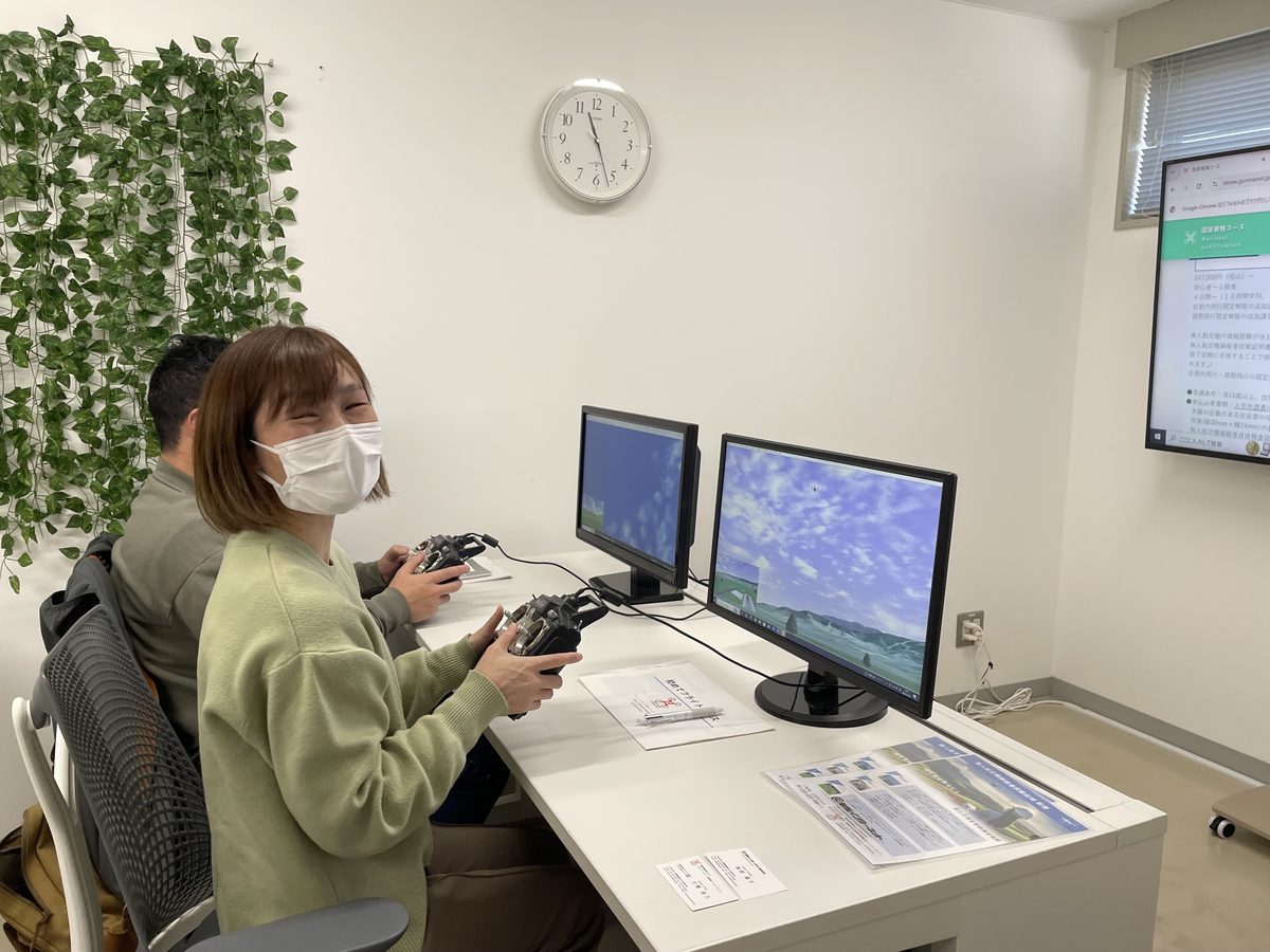 学科会場のシミュレーターで、送信機を持って操縦を練習する受講者